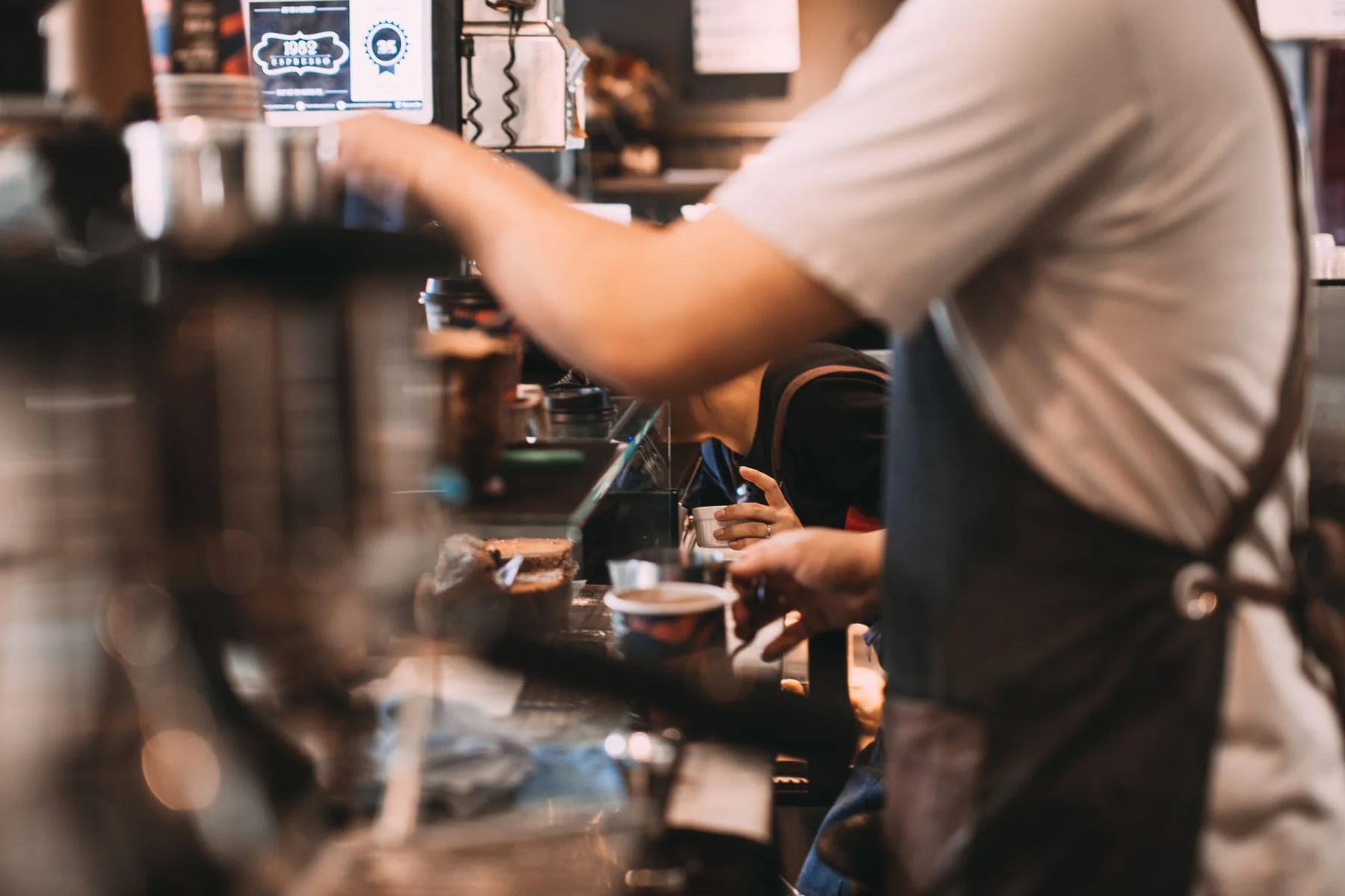 A barista working at an espresso machine in a coffee shop